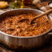 Pentola appoggiata su di un tavolo con all'interno un ragù di carne come vuole la tradizione italiana